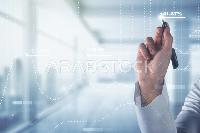 صورة مقربة ليد رجل عربي خليجي سعودي، دراسة السوق المالي والجدوة المالية، تحليل البيانات ورسمها بتقنية الهولوجرام، تخطيط وتحليل البيانات و المعلومات