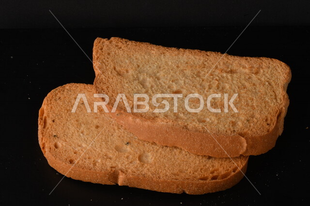 صورة مقربة لمجموعة من نباتات القمح ، وشرائح خبز التوست المحمصة على خلفية سوداء