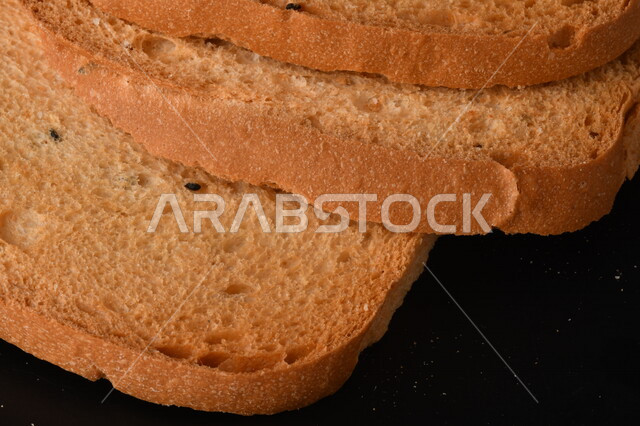 صورة مقربة لمجموعة من نباتات القمح ، وشرائح خبز التوست المحمصة على خلفية سوداء