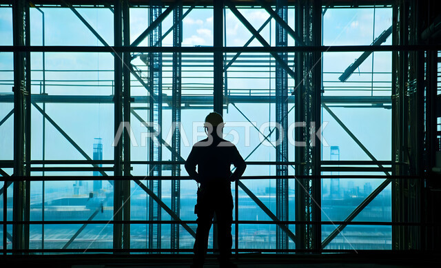 Supervising and following up on projects, growth and progress of the engineering sector, development of construction engineering in Saudi Arabia, silhouette of a Saudi Arabian Gulf engineer wearing a safety helmet managing the project from the work site, professions and jobs in the Kingdom, cellulite