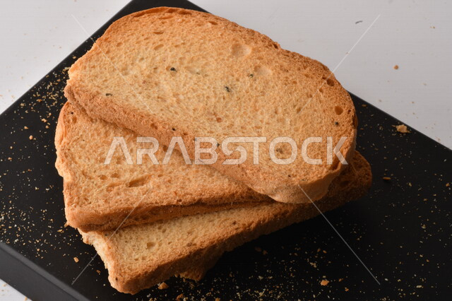 شرائح البقسماط المقرمشة على لوحة التقطيع سوداء اللون ، صورة مقربة لمخبوزات طازجة محمصة