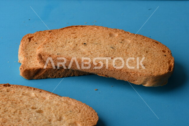 شرائح البقسماط المقرمشة على لوحة التقطيع زرقاء اللون ، صورة مقربة لمخبوزات طازجة محمصة