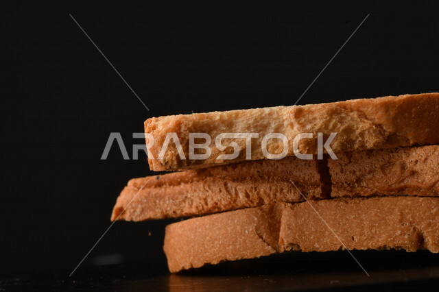 صورة لشرائح البقسماط المقرمشة على خلفية سوداء ، صورة مقربة لمخبوزات طازجة محمصة ، الشابورة