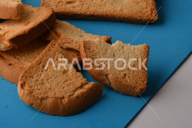 شرائح البقسماط المقرمشة المقطعة على لوحة التقطيع زرقاء اللون ، صورة مقربة لمخبوزات طازجة محمصة ، الشابورة