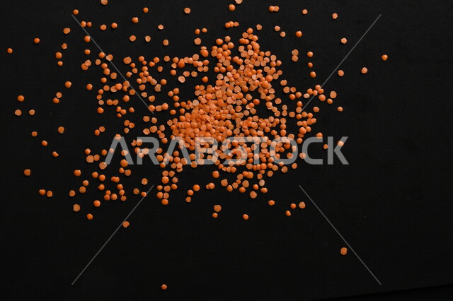 صورة مقربة لمجموعة من حبوب العدس الأحمر على خلفية سوداء ، بذور نباتي غذائي صحي ، حبوب العدس النباتي الجاف