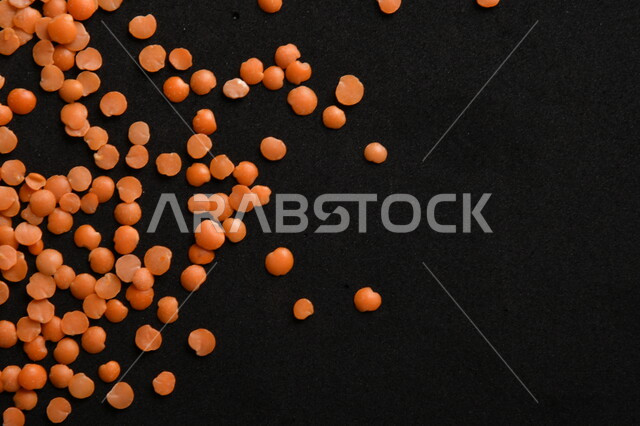 صورة مقربة لمجموعة من حبوب العدس الأحمر على خلفية سوداء ، بذور نباتي غذائي صحي ، حبوب العدس النباتي الجاف