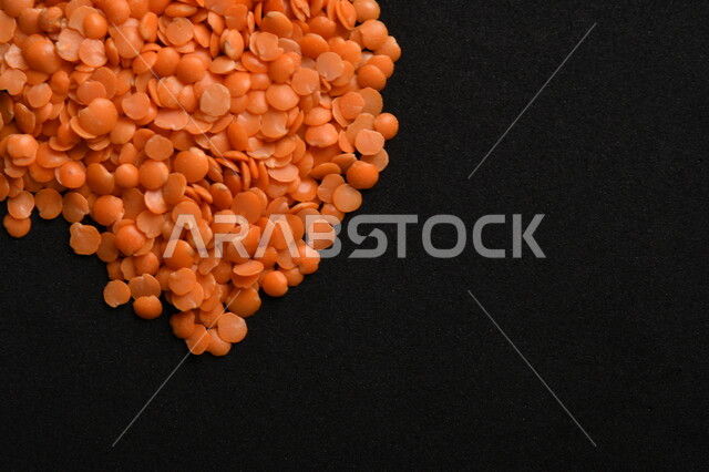 صورة مقربة لمجموعة من حبوب العدس الأحمر على خلفية سوداء ، بذور نباتي غذائي صحي ، حبوب العدس النباتي الجاف