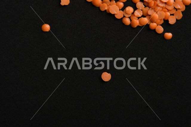 صورة مقربة لمجموعة من حبوب العدس الأحمر على خلفية سوداء ، بذور نباتي غذائي صحي ، حبوب العدس النباتي الجاف