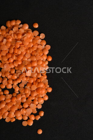 صورة مقربة لمجموعة من حبوب العدس الأحمر على خلفية سوداء ، بذور نباتي غذائي صحي ، حبوب العدس النباتي الجاف