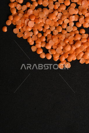 صورة مقربة لمجموعة من حبوب العدس الأحمر على خلفية سوداء ، بذور نباتي غذائي صحي ، حبوب العدس النباتي الجاف