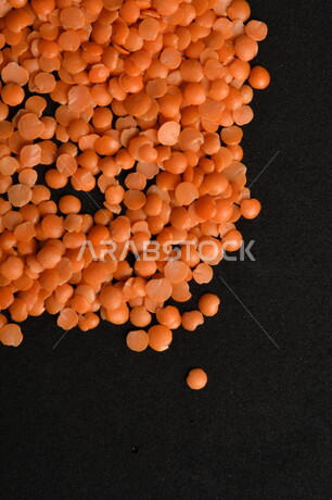 صورة مقربة لمجموعة من حبوب العدس الأحمر على خلفية سوداء ، بذور نباتي غذائي صحي ، حبوب العدس النباتي الجاف