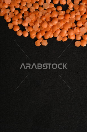 صورة مقربة لمجموعة من حبوب العدس الأحمر على خلفية سوداء ، بذور نباتي غذائي صحي ، حبوب العدس النباتي الجاف