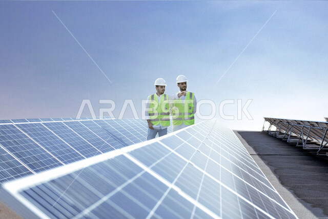 مهندسان كهربائيان عربيان خليجيان سعوديان يتفقدان تركيب الخلايا الشمسية على السطح ، استخدام الطاقة الشمسية لتوليد الكهرباء ، مفهوم استخدام الطاقة المتجددة ، مفهوم التنمية المستدامة بالطاقة البديلة