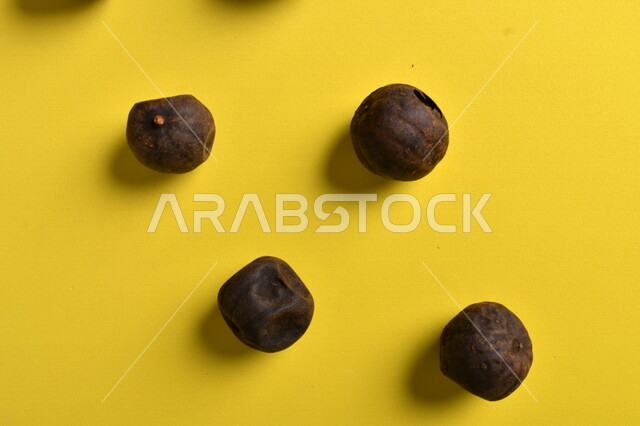 صورة لثمار الجير الأسود المجفف على خلفية صفراء ، الليمون العماني المجفف ، ثمرة الليمون الحامض المجفف ، توابل وبهارات مجففة