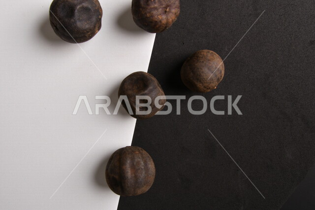 صورة لثمار الجير الأسود المجفف على خلفية سوداء وبيضاء ، الليمون العماني المجفف ، ثمرة الليمون الحامض المجفف ، توابل وبهارات مجففة