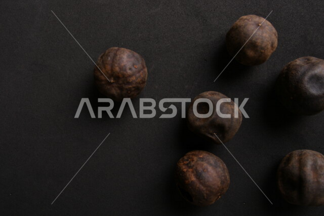 Image of dried black lime fruits on black background, dried Omani lemon, dried lime fruit, dried spices and seasonings