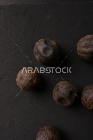 صورة لثمار الجير الأسود المجفف على خلفية سوداء ، الليمون العماني المجفف ، ثمرة الليمون الحامض المجفف ، توابل وبهارات مجففة