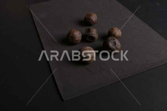 صورة لثمار الجير الأسود المجفف على خلفية سوداء ، الليمون العماني المجفف ، ثمرة الليمون الحامض المجفف ، توابل وبهارات مجففة