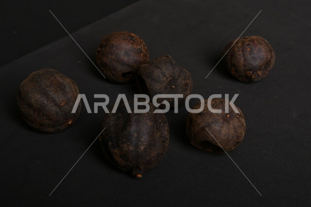 Image of dried black lime fruits on black background, dried Omani lemon, dried lime fruit, dried spices and seasonings