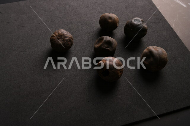 صورة لثمار الجير الأسود المجفف على خلفية سوداء ، الليمون العماني المجفف ، ثمرة الليمون الحامض المجفف ، توابل وبهارات مجففة