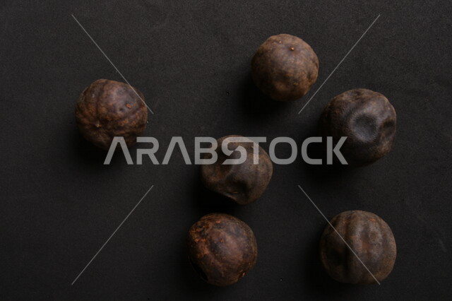 صورة لثمار الجير الأسود المجفف على خلفية سوداء ، الليمون العماني المجفف ، ثمرة الليمون الحامض المجفف ، توابل وبهارات مجففة