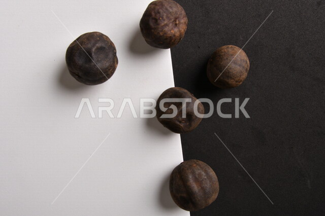 Image of dried black lime fruits on black and white background, dried Omani lemon, dried lime fruit, dried spices and seasonings