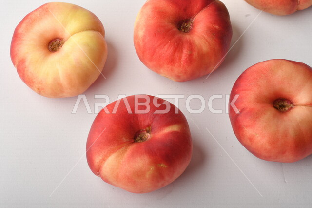 فاكهة الخوخ المسطح اللذيذ على خلفية بيضاء ، ثمرة الدّراق الصحية اللذيذة ، فاكهة الدُّراق المُبلَّط وتسمى كعب الغزال ، فاكهة صيفية