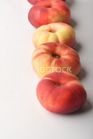 فاكهة الخوخ المسطح اللذيذ على خلفية بيضاء ، ثمرة الدّراق الصحية اللذيذة ، فاكهة الدُّراق المُبلَّط وتسمى كعب الغزال ، فاكهة صيفية