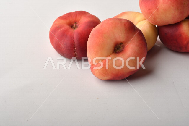 فاكهة الخوخ المسطح اللذيذ على خلفية بيضاء ، ثمرة الدّراق الصحية اللذيذة ، فاكهة الدُّراق المُبلَّط وتسمى كعب الغزال ، فاكهة صيفية