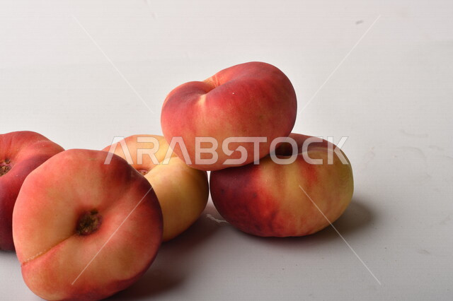 فاكهة الخوخ المسطح اللذيذ على خلفية بيضاء ، ثمرة الدّراق الصحية اللذيذة ، فاكهة الدُّراق المُبلَّط وتسمى كعب الغزال ، فاكهة صيفية