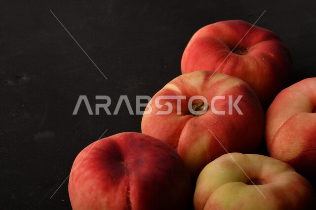 صورة لفاكهة الخوخ المسطح اللذيذ على خلفية سوداء ، ثمرة الدّراق الصحية اللذيذة ، فاكهة الدُّراق المُبلَّط وتسمى كعب الغزال ، فاكهة صيفية