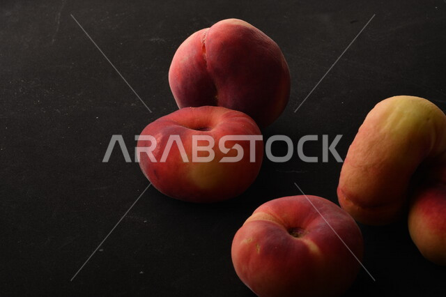 صورة لفاكهة الخوخ المسطح اللذيذ على خلفية سوداء ، ثمرة الدّراق الصحية اللذيذة ، فاكهة الدُّراق المُبلَّط وتسمى كعب الغزال ، فاكهة صيفية