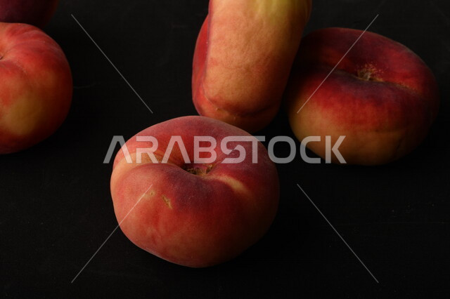 صورة لفاكهة الخوخ المسطح اللذيذ على خلفية سوداء ، ثمرة الدّراق الصحية اللذيذة ، فاكهة الدُّراق المُبلَّط وتسمى كعب الغزال ، فاكهة صيفية