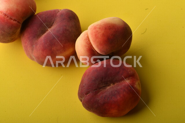 صورة لفاكهة الخوخ المسطح اللذيذ على خلفية صفراء ، ثمرة الدّراق الصحية اللذيذة ، فاكهة الدُّراق المُبلَّط وتسمى كعب الغزال ، فاكهة صيفية