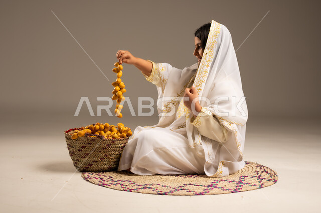 Anniversary of the founding of the first Saudi state, February 22, date harvest season, close-up portrait from the side of a Saudi Arabian Gulf girl wearing a sheila and a neshel holding fresh dates in her hand, the day of our beginning 1727 AD, wearing the costumes of the Eastern Province, local and national agricultural products and crops, beige background
