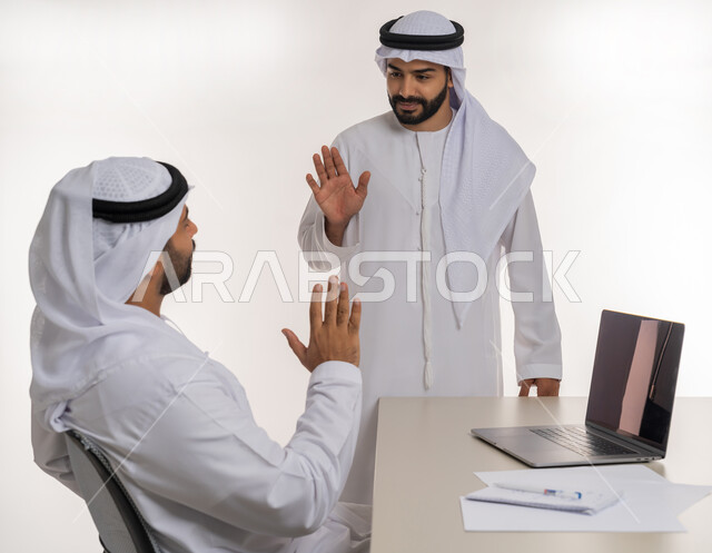 مهن ووظائف مكتبية, مفهوم التعاون بين الموظفين, التفاعل الجماعي لتحقيق أهداف الشركة, دمج التقنيات الحديثة المتطورة في الحياة العملية, بورتريه لموظفين عربيين خليجيين اماراتيين مبتسمين يرتديان الغترة والكندورة البيضاء يلقيان التحية, خلفية بيضاء