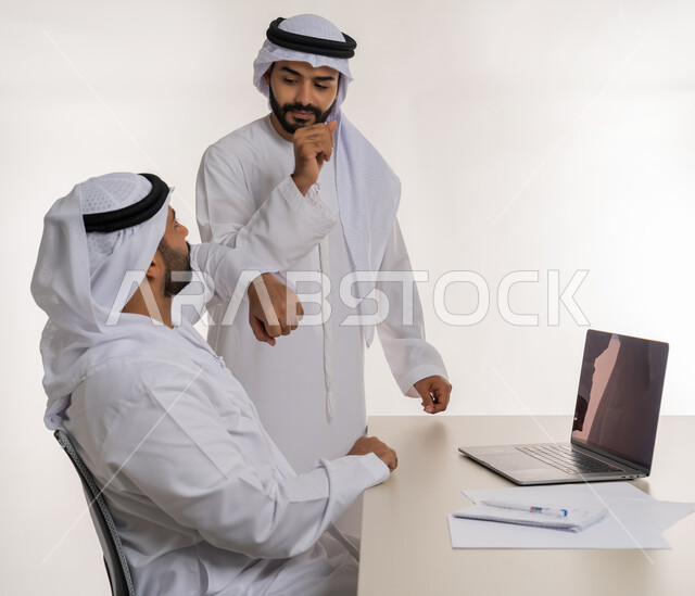 مهن ووظائف مكتبية, مفهوم التعاون بين الموظفين, التفاعل الجماعي لتحقيق أهداف الشركة, دمج التقنيات الحديثة المتطورة في الحياة العملية, بورتريه لموظفين عربيين خليجيين اماراتيين مبتسمين يرتديان الغترة والكندورة البيضاء يتصافحان بالاكواع, خلفية بيضاء