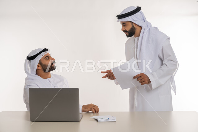 عقد صفقات شراكة جديدة، مفهوم الإدارة المتعاونة، بورتريه مقرب لموظفين عربيين خليجيين اماراتيين مبتسمين يرتديان الغترة والكندورة البيضاء يتناقشان بأمور العمل باستخدام الأوراق والبيانات، الوحدة والتفاعل الجماعي لتحقيق أهداف الشركة وحل المشكلات، خلفية بيضاء