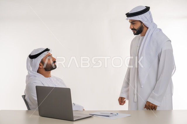الوحدة والتفاعل الجماعي لتحقيق أهداف الشركة وحل المشكلات، بورتريه لموظفين عربيين خليجيين اماراتيين يرتديان الغترة والكندورة البيضاء يتناقشان بأمور العمل, مهن ووظائف مكتبية, خلفية بيضاء