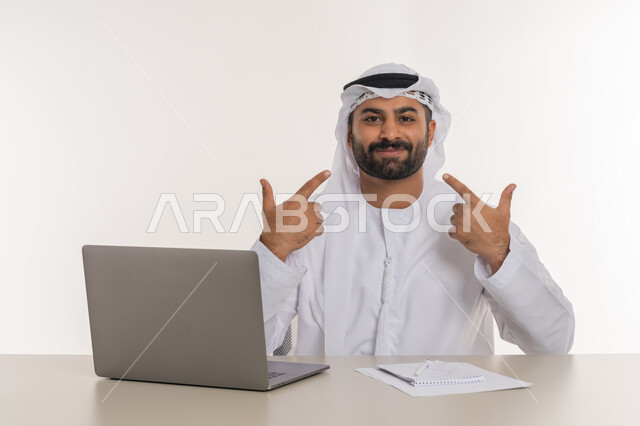 انجاز المهام وتحقيق الاهداف, مهن ووظائف مكتبية, بورتريه لرجل عربي خليجي اماراتي يرتدي الغترة والكندورة البيضاء يشير باصبعه الى  وجهه بايماءات السرور والرضا, خلفية بيضاء