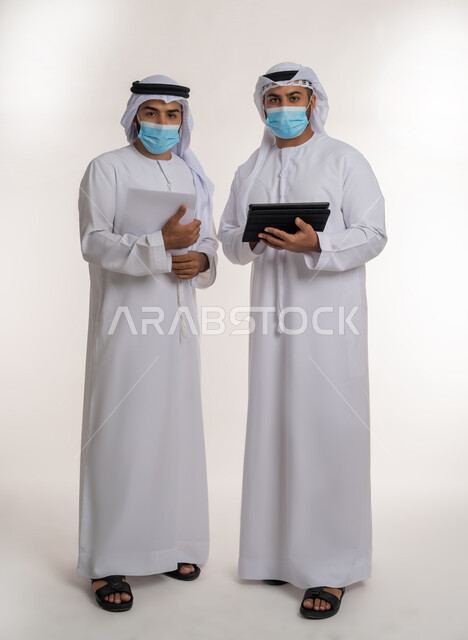 عقد صفقات شراكة جديدة، تحقيق أهداف الشركة وحل المشكلات, مفهوم الإدارة المتعاونة، بورتريه لموظفين عربيين خليجيين اماراتيين يرتديان الغترة والكندورة والكمامة ينظران الى الكاميرا بإيماءات الثقة بالنفس والجدية، اتباع الاجراءات الوقائية ضد كوفيد19, الجسم بالطول الكامل, خلفية بيضاء