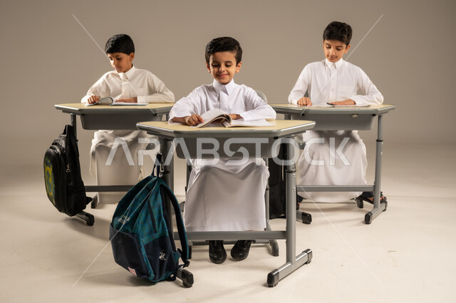 موسم العودة إلى المدارس، بورتريه لمجموعة من الطلاب العربيين الخليجيين السعوديين يرتدون الزي المدرسي يجلسون في مقاعدهم وأمامهم الكتب والمقررات المدرسية، أهداف التربية والتعليم في المملكة العربية السعودية، جودة أساليب التعلم الفعال والمناهج الحديثة، خلفية رمادية