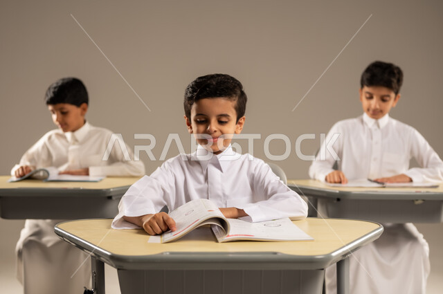 موسم العودة إلى المدارس، بورتريه لمجموعة من الطلاب العربيين الخليجيين السعوديين يرتدون الزي المدرسي يجلسون في مقاعدهم وأمامهم الكتب والمقررات المدرسية، أهداف التربية والتعليم في المملكة العربية السعودية، جودة أساليب التعلم الفعال والمناهج الحديثة، خلفية رمادية