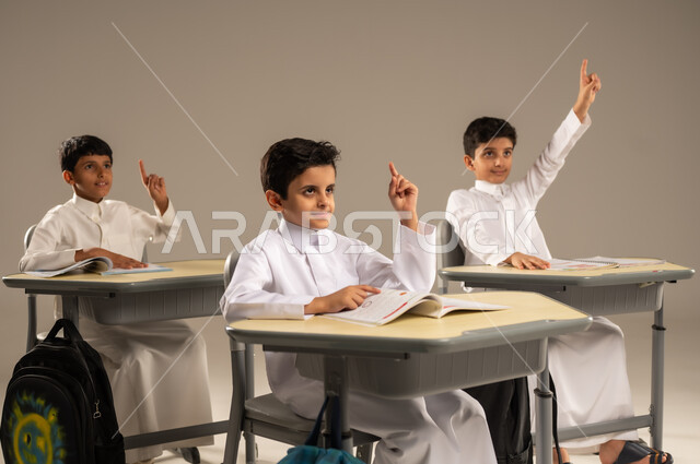 أهداف التربية والتعليم في المملكة العربية السعودية، أساليب التعلم الفعال والمشاركة مع المعلم، موسم العودة إلى المدارس، بورتريه لمجموعة من الطلاب العربيين الخليجيين السعوديين يرتدون الزي المدرسي يجلسون في مقاعدهم وأمامهم الكتب والمقررات المدرسية، خلفية رمادية