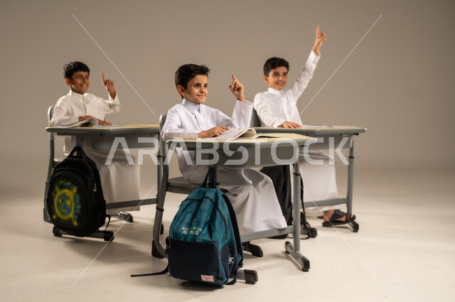 أهداف التربية والتعليم في المملكة العربية السعودية، أساليب التعلم الفعال والمشاركة مع المعلم، موسم العودة إلى المدارس، بورتريه لمجموعة من الطلاب العربيين الخليجيين السعوديين يرتدون الزي المدرسي يجلسون في مقاعدهم وأمامهم الكتب والمقررات المدرسية، خلفية رمادية