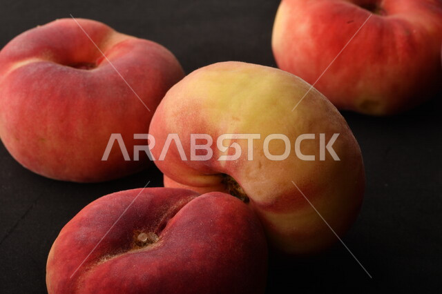 صورة لفاكهة الخوخ المسطح اللذيذ على خلفية سوداء ، ثمرة الدّراق الصحية اللذيذة ، فاكهة الدُّراق المُبلَّط وتسمى كعب الغزال ، فاكهة صيفية