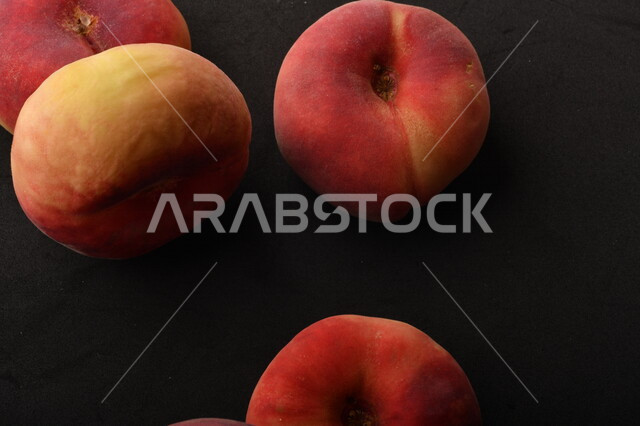 صورة لفاكهة الخوخ المسطح اللذيذ على خلفية سوداء ، ثمرة الدّراق الصحية اللذيذة ، فاكهة الدُّراق المُبلَّط وتسمى كعب الغزال ، فاكهة صيفية