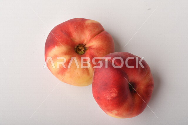 فاكهة الخوخ المسطح اللذيذ على خلفية بيضاء ، ثمرة الدّراق الصحية اللذيذة ، فاكهة الدُّراق المُبلَّط وتسمى كعب الغزال ، فاكهة صيفية