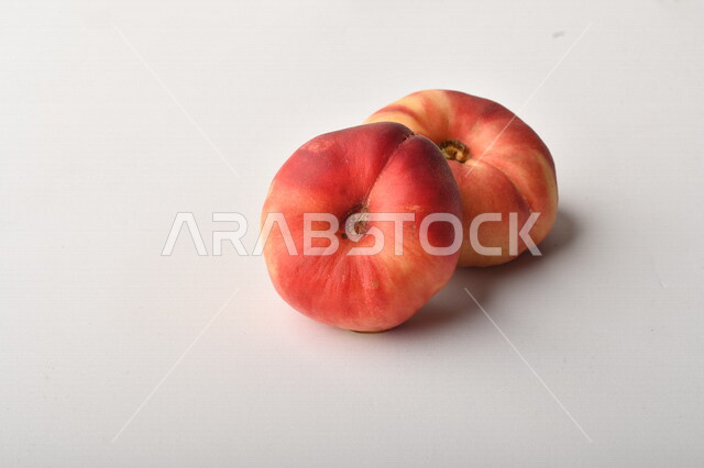 فاكهة الخوخ المسطح اللذيذ على خلفية بيضاء ، ثمرة الدّراق الصحية اللذيذة ، فاكهة الدُّراق المُبلَّط وتسمى كعب الغزال ، فاكهة صيفية