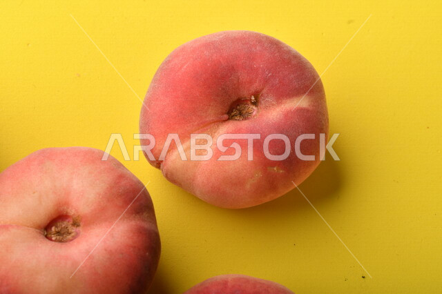 صورة لفاكهة الخوخ المسطح اللذيذ على خلفية صفراء ، ثمرة الدّراق الصحية اللذيذة ، فاكهة الدُّراق المُبلَّط وتسمى كعب الغزال ، فاكهة صيفية